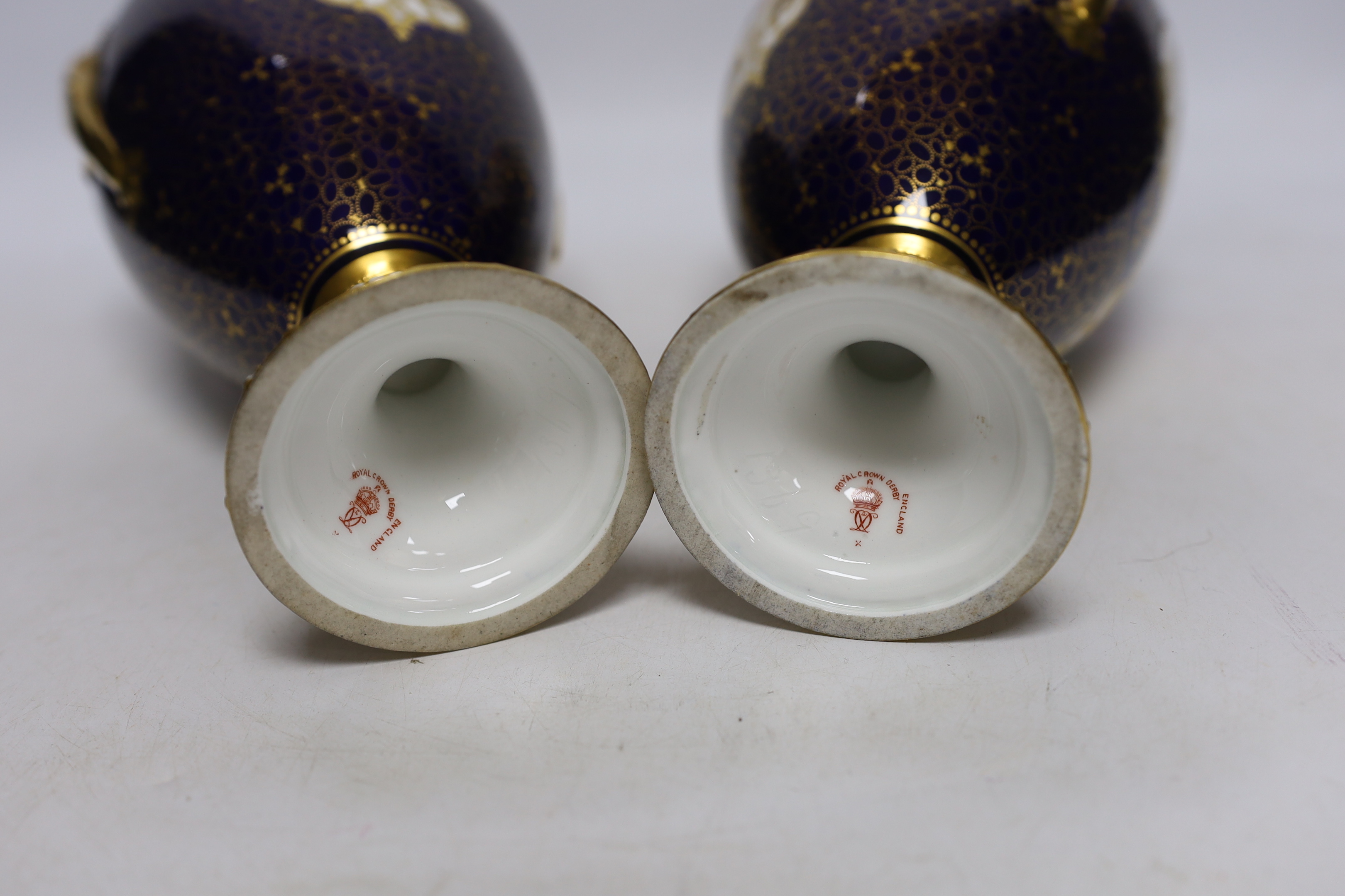A pair of Royal Crown Derby porcelain urns and covers together with a smaller example and an Imari style jar and cover, 36cm high